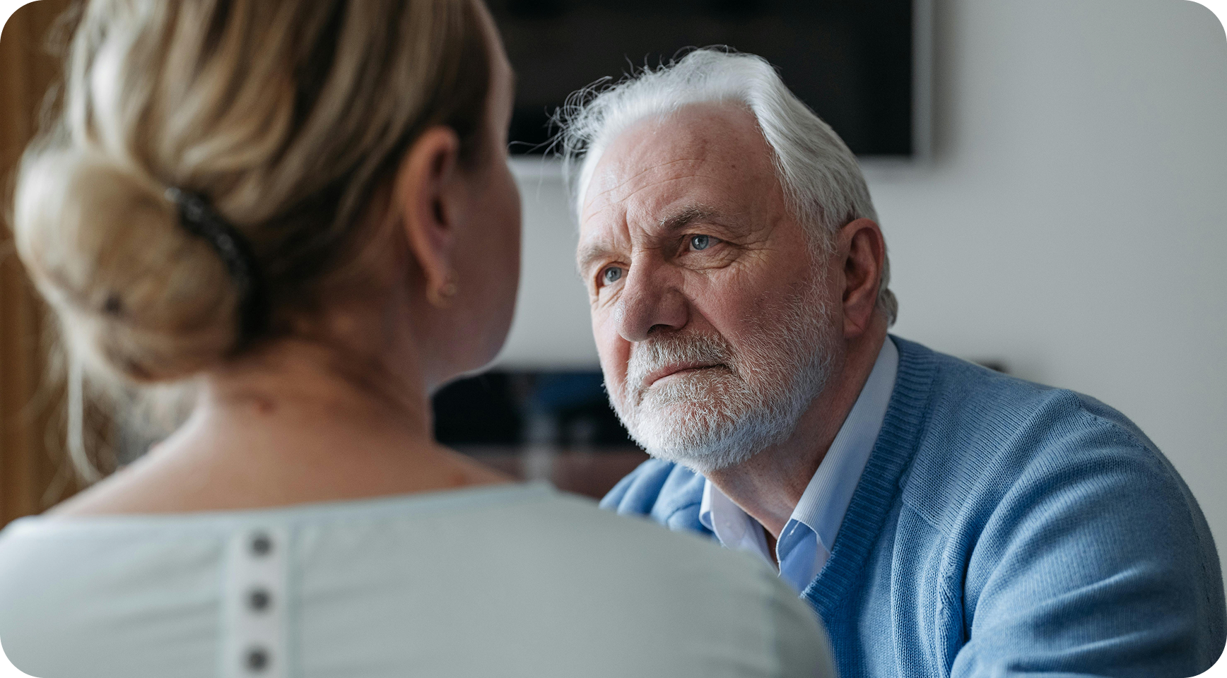 An older man sitting in conversation with a woman during a funeral arrangement meeting.