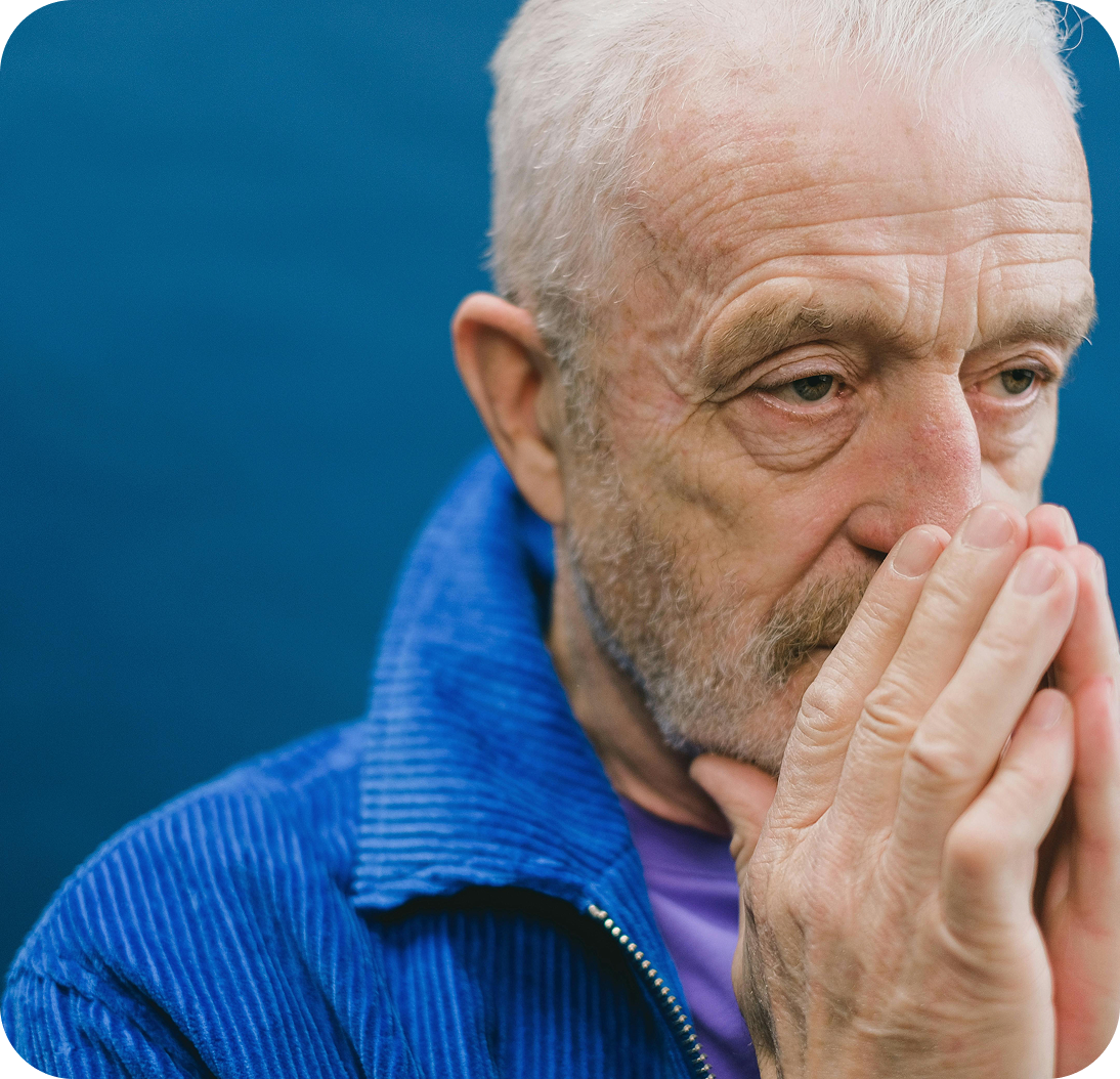 An older man in a blue jacket sitting in reflection.